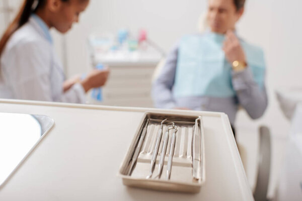 selective focus of dental instruments near african american dentist and patient 