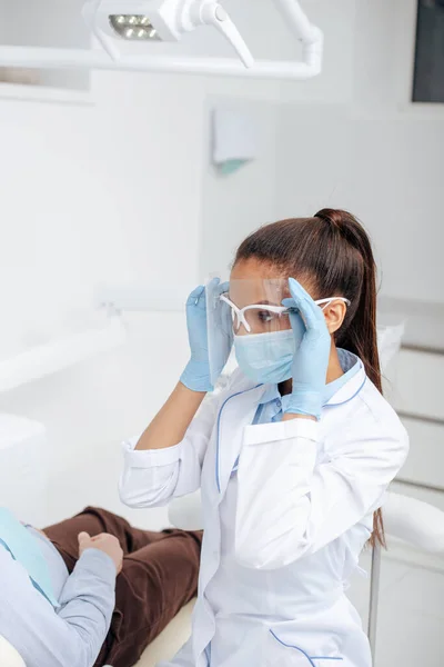 Dentista Afro Americano Máscara Médica Tocando Protetor Facial Perto Paciente — Fotografia de Stock