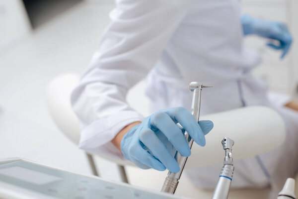 cropped view of dentist taking stainless dental instrument 