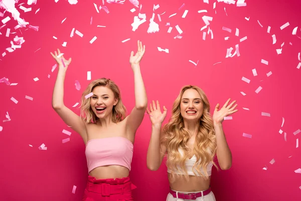 Vrolijke Blonde Vrienden Glimlachen Camera Onder Vallende Confetti Roze Achtergrond — Stockfoto