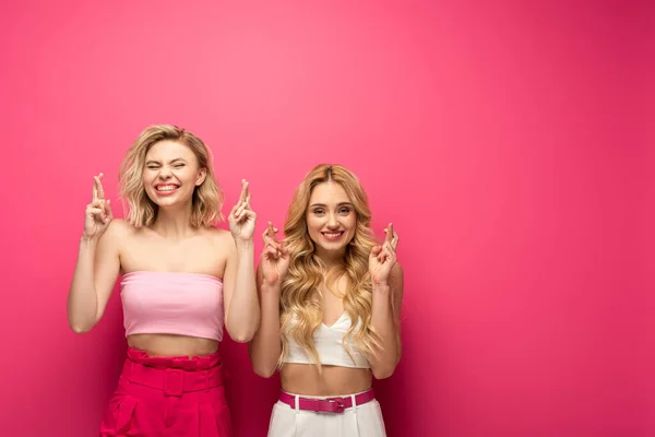 Felices Amigas Rubias Con Dedos Cruzados Sobre Fondo Rosa — Foto de Stock