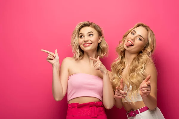 Sonrientes Amigas Rubias Señalando Con Los Buscadores Sobre Fondo Rosa —  Fotos de Stock