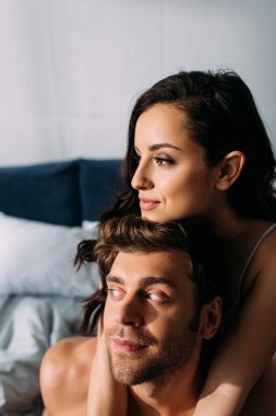 Kız arkadaşın başka tarafa bakıyor, gülümsüyor ve erkek arkadaşına sarılıyor.