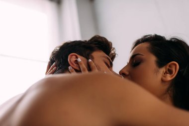 Yatak odasında öpüşen ve sarılan kapalı gözlü çiftlerin seçici odağı.