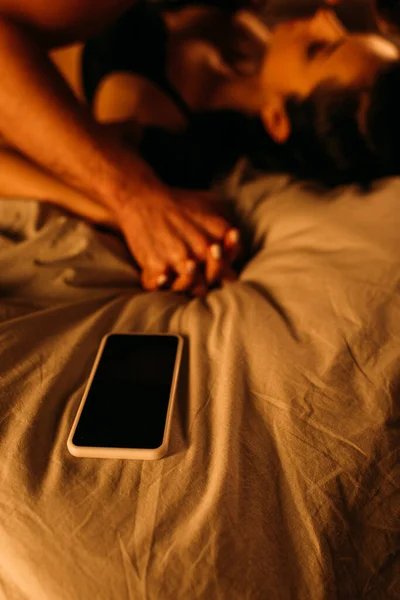 Selective Focus Couple Clenched Hands Lying Smartphone Bed Bedroom — Stock Photo, Image