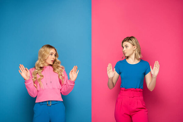 Confused blonde girls showing stop gesture on pink and blue background