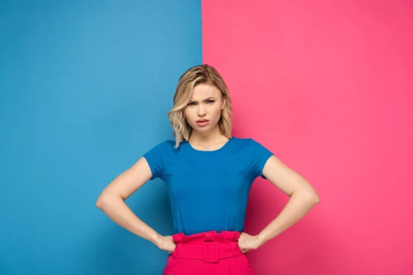 Angry Blonde Girl Hands Hips Looking Camera Pink Blue Background — Stock Photo, Image