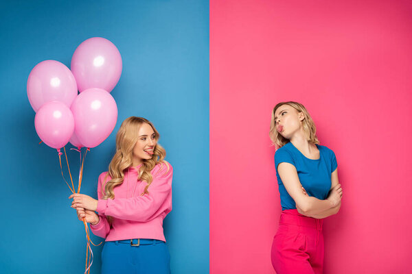 Blonde girl with balloons sticking out tongue at offended sister on blue and pink background