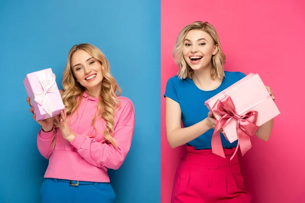 Happy Blonde Women Holding Gift Boxes Bows Blue Pink Background — Stock Photo, Image