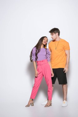 Beyaz arka planda yakışıklı bir genç adamın yanındaki kameraya bakan Afro-Amerikan kız manzarası.