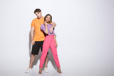 Beyaz arka planda modaya uyan Afro-Amerikan kız arkadaşının el ele tutuşan yakışıklı adamın geniş görüşü.