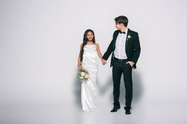 Güzel Afro-Amerikan gelini ile el ele tutuşup beyaz arka planda el ele tutuşan yakışıklı damat manzarası
