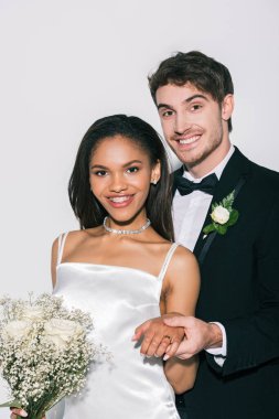Güzel Afrikalı Amerikalı gelinin beyaz arka planda düğününü gösteren neşeli damat.