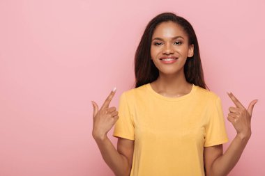 Gülümseyen Afrikalı Amerikalı kız pembe dişlerindeki diş tellerini işaret ediyor.