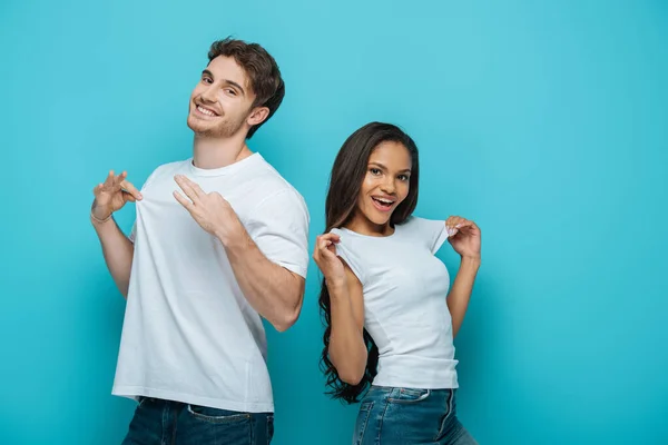 Fröhliches Gemischtrassiges Paar Das Weiße Shirts Auf Blauem Hintergrund Berührt — Stockfoto