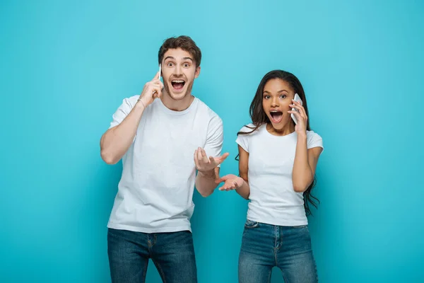 Excited Interracial Couple Talking Smartphones While Standing Open Arms Blue — Stock Photo, Image