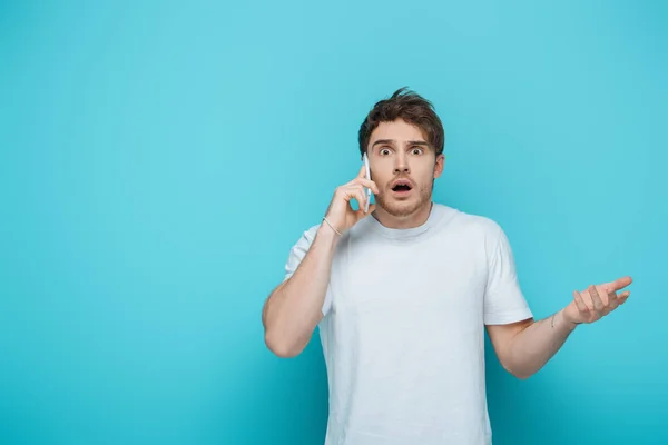 Shocked Man Standing Open Arm While Talking Smartphone Blue Background — Stock Photo, Image