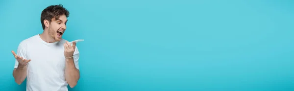 Vízszintes Kép Dühös Fiatalember Sikoltozó Okostelefon Elszigetelt Kék — Stock Fotó