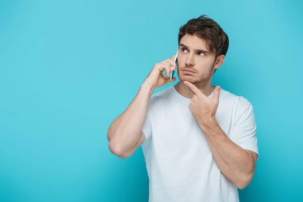 Thoughtful Guy Touching Chin While Talking Smartphone Looking Away Blue — Stock Photo, Image