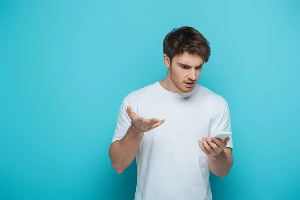 Displeased Young Man Looking Smartphone While Standing Open Arm Blue — Stock Photo, Image