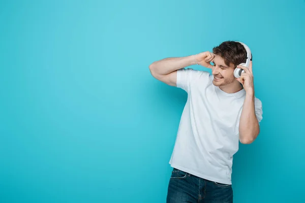 Opgewonden Jonge Man Aanraken Van Draadloze Hoofdtelefoon Tijdens Het Luisteren — Stockfoto