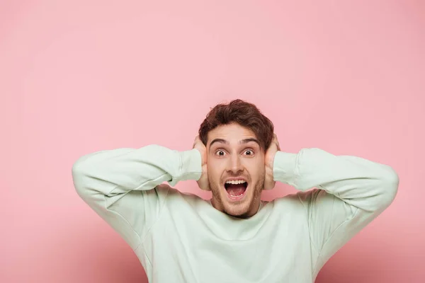 Φοβισμένος Άνθρωπος Ουρλιάζοντας Ενώ Καλύπτει Αυτιά Χέρια Ροζ Φόντο — Φωτογραφία Αρχείου