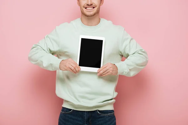 ピンクの背景に白い画面のデジタルタブレットを見せる笑顔の男のクロップドビュー — ストック写真