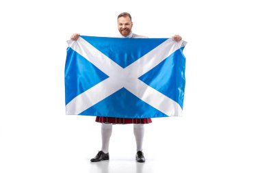 smiling Scottish redhead man in red kilt with flag of Scotland on white background clipart