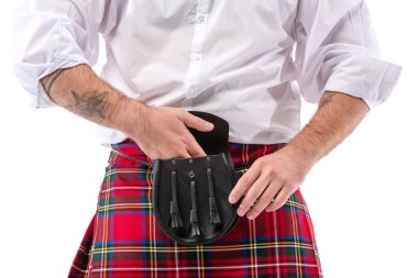 Kırmızılı İskoç adamın beyaz tenli deri kemer çantasına elini koyması.