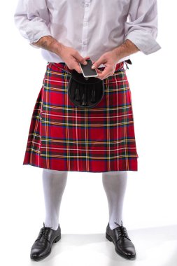 Kırmızılı İskoç adamın deri kemer çantası ve beyaz arka planda akıllı telefonu vardı.