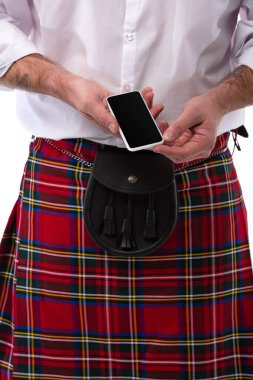cropped view of Scottish man in red kilt with leather belt bag and smartphone isolated on white clipart
