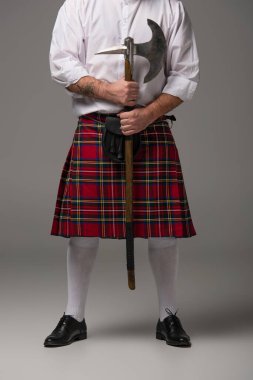 cropped view of Scottish man in red kilt with battle axe on grey background clipart