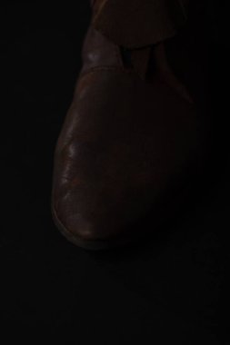 close up view of medieval Scottish brown leather shoes isolated on black clipart