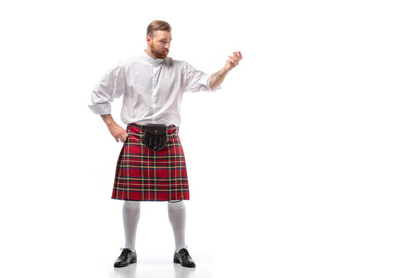 serious Scottish redhead man in red kilt on white background