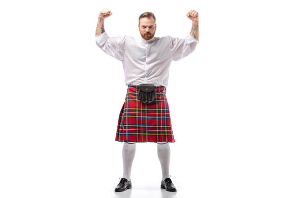 strong Scottish redhead man in red kilt showing fists on white background