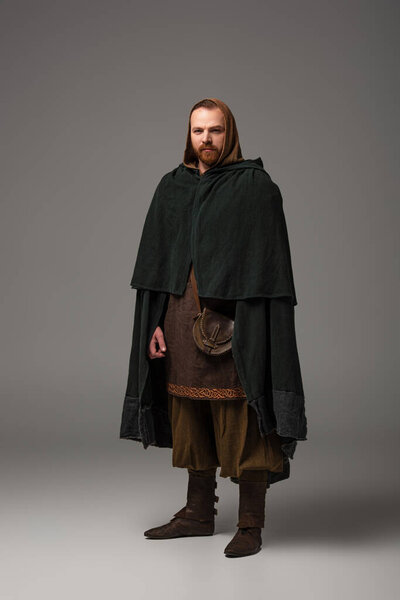 medieval Scottish redhead man in mantel on grey background