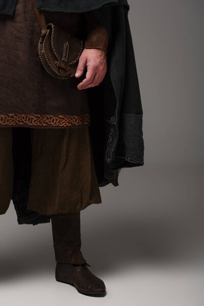 cropped view of medieval Scottish man in mantel on grey background