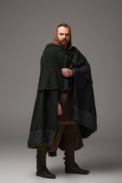 medieval Scottish redhead man in mantel on grey background
