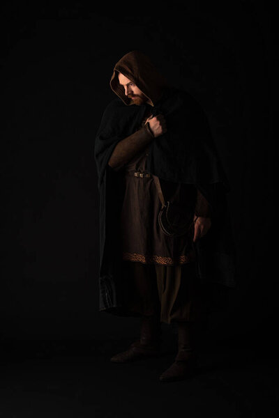 medieval Scottish redhead man in mantel on dark isolated on black