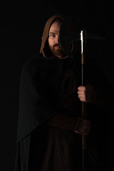 medieval Scottish warrior with battle axe in mantel isolated on black