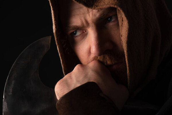 задумчивый средневековый шотландский воин с боевым топором, изолированным от черного
