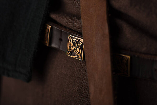 крупный план средневековой шотландской коричневой одежды и пояса с золотой пряжкой

