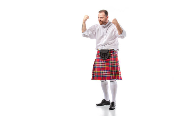Scottish redhead bearded man in red tartan kilt showing yeah gesture on white background