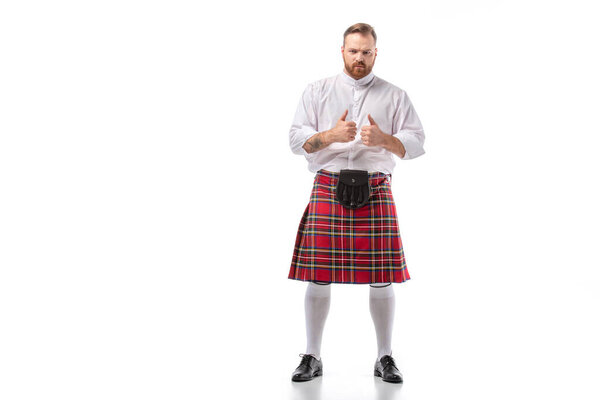 Scottish redhead bearded man in red tartan kilt showing thumbs up on white background