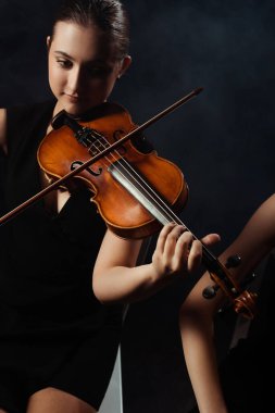 profesyonel güzel müzisyenler karanlık sahnede keman çalıyorlar. 