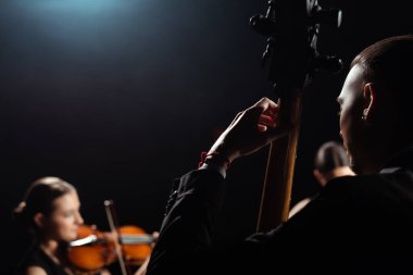 trio of professional musicians playing on musical instruments on dark stage clipart