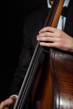cropped view of male musician playing on contrabass isolated on black clipart