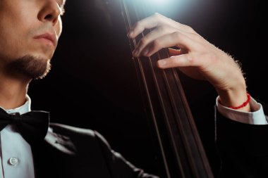 cropped view of musician playing on contrabass on dark stage with back light clipart