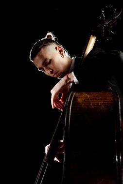male professional musician playing on double bass isolated on black clipart