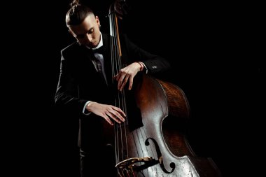 male musician playing on contrabass isolated on black clipart